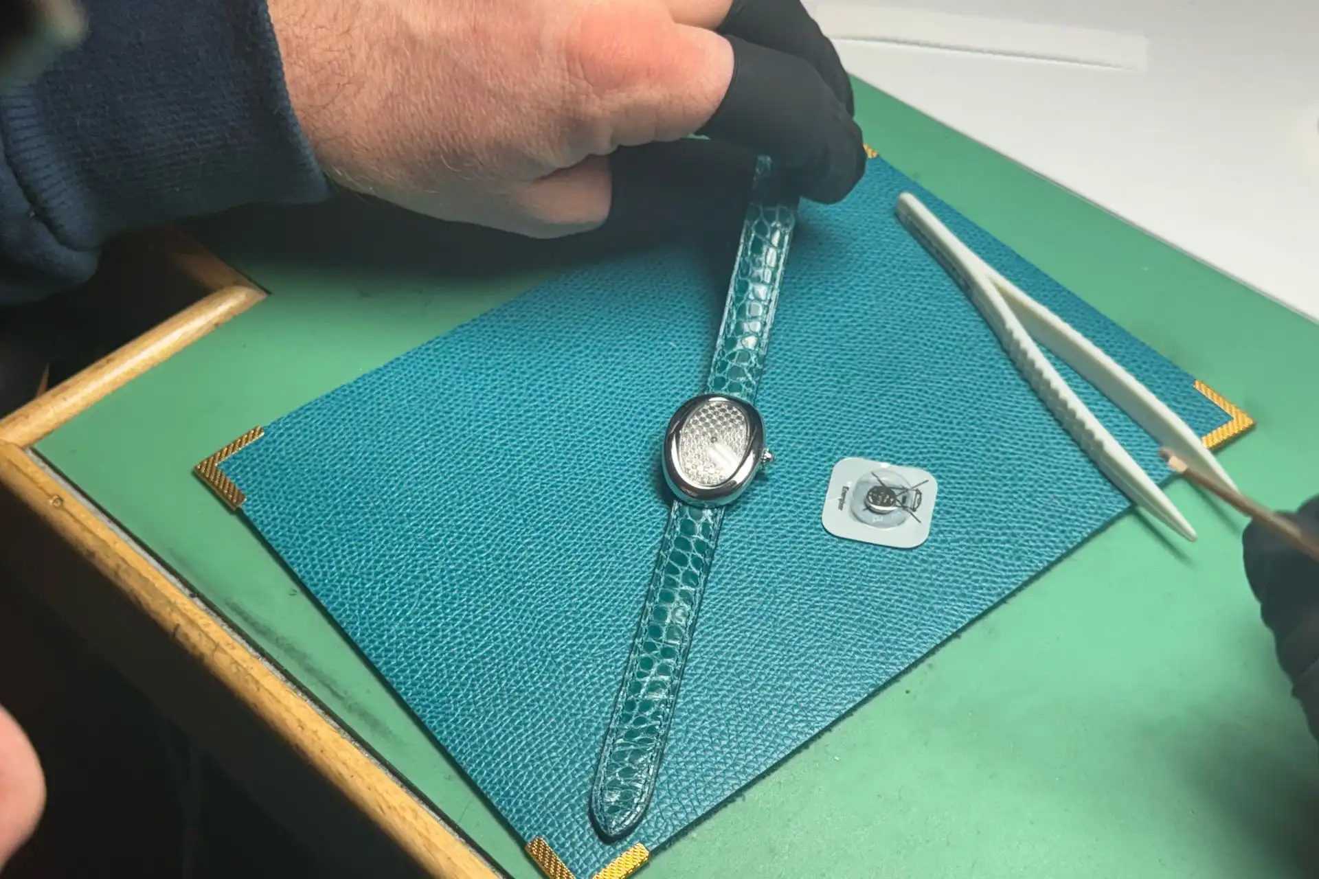 Changement de pile sur une montre de luxe dans un atelier horloger à Genève.