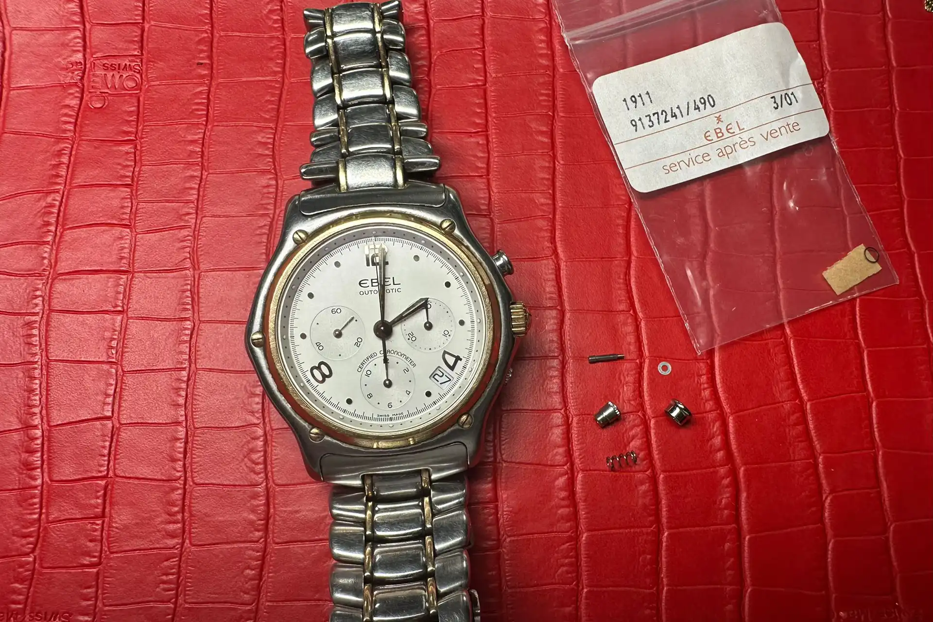 Montre Ebel 1911 démontée – Service après-vente Vue d’une montre Ebel 1911 démontée avec pièces détachées